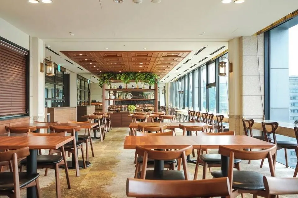 A restaurant floor of teak tables and curved-back wooden chairs